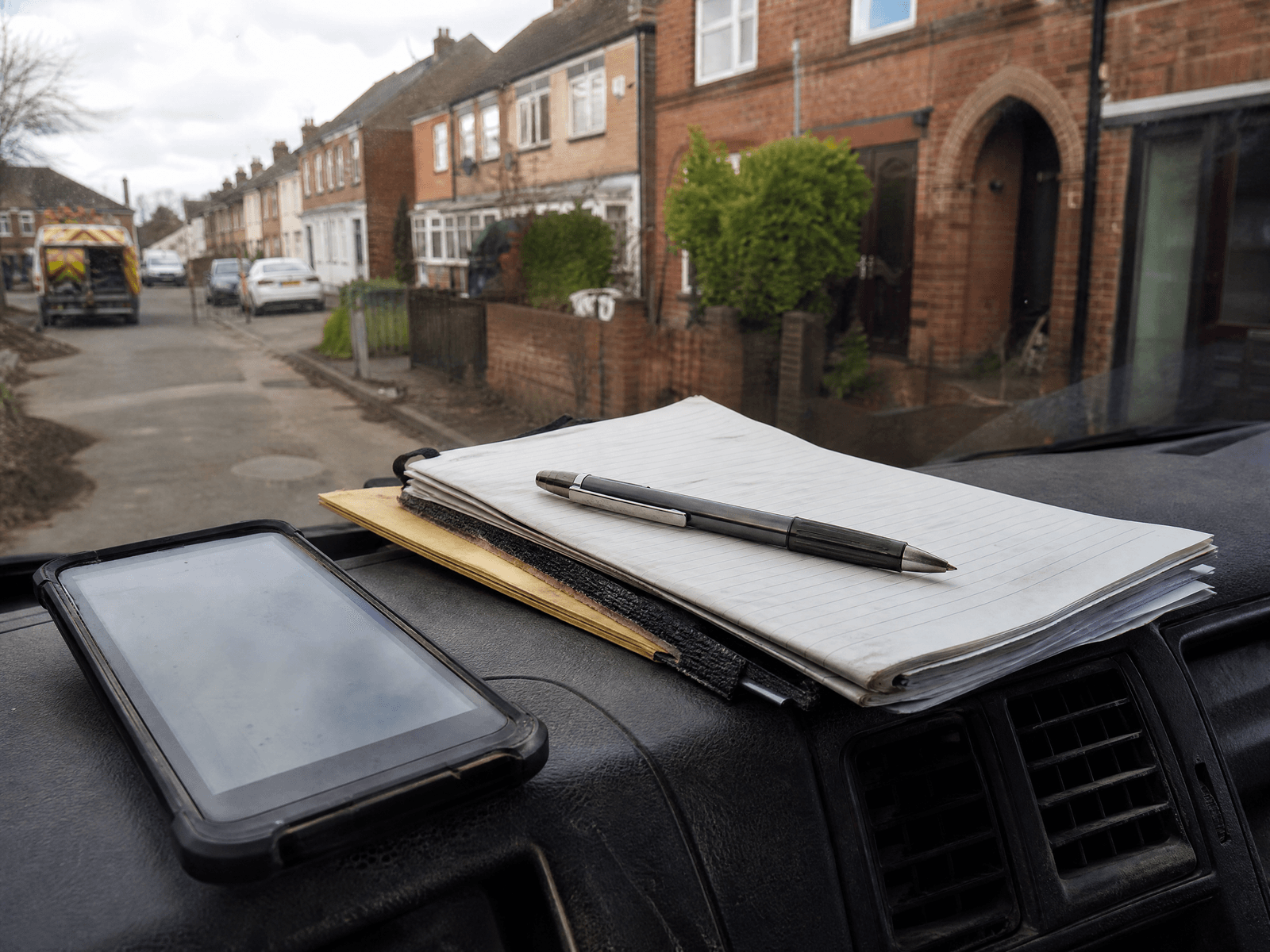 Phone on a van dashboard next to a job notebook