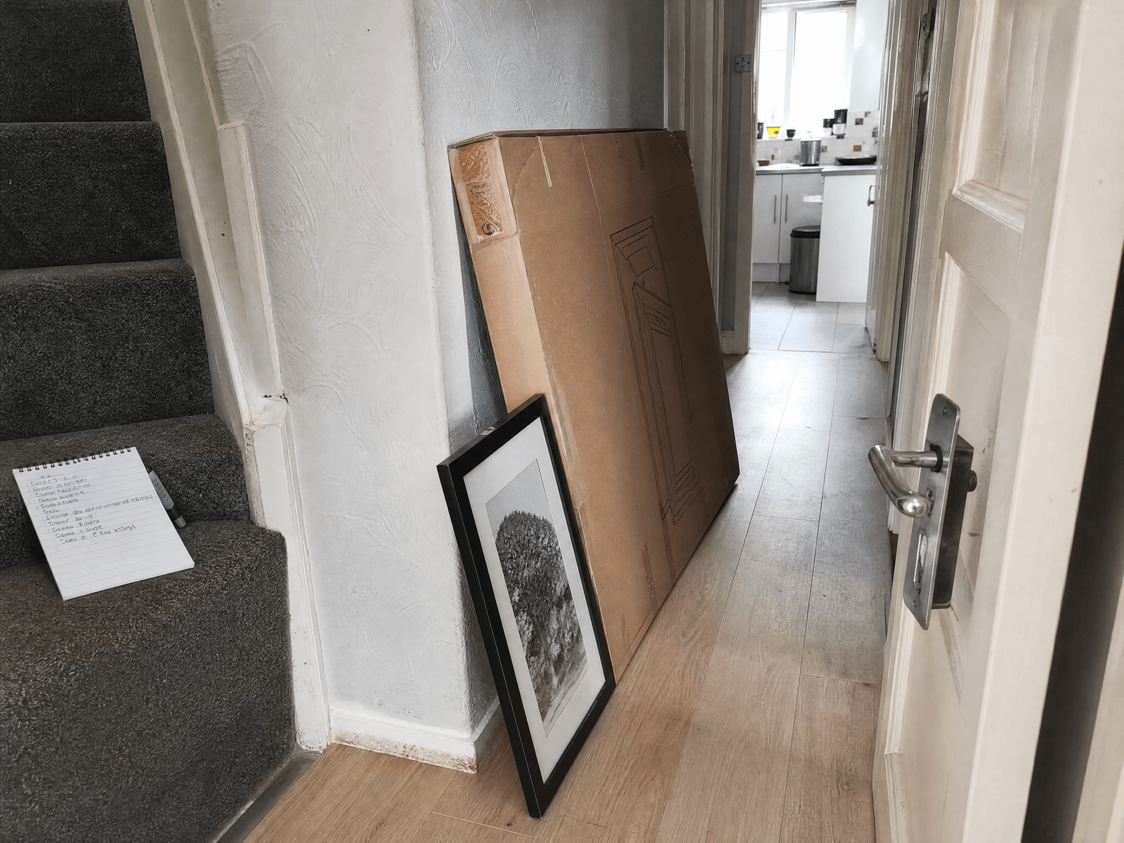 Hallway with a list of small jobs: a loose door handle, an unhung picture and a flat pack box