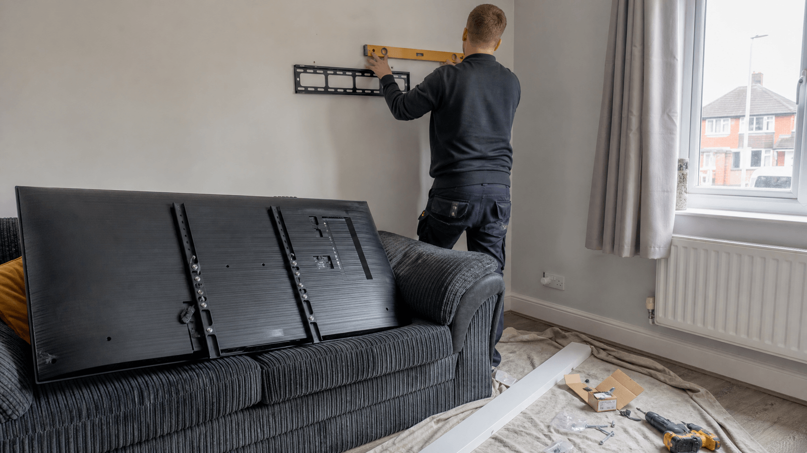TV being fixed to a living room wall on a bracket